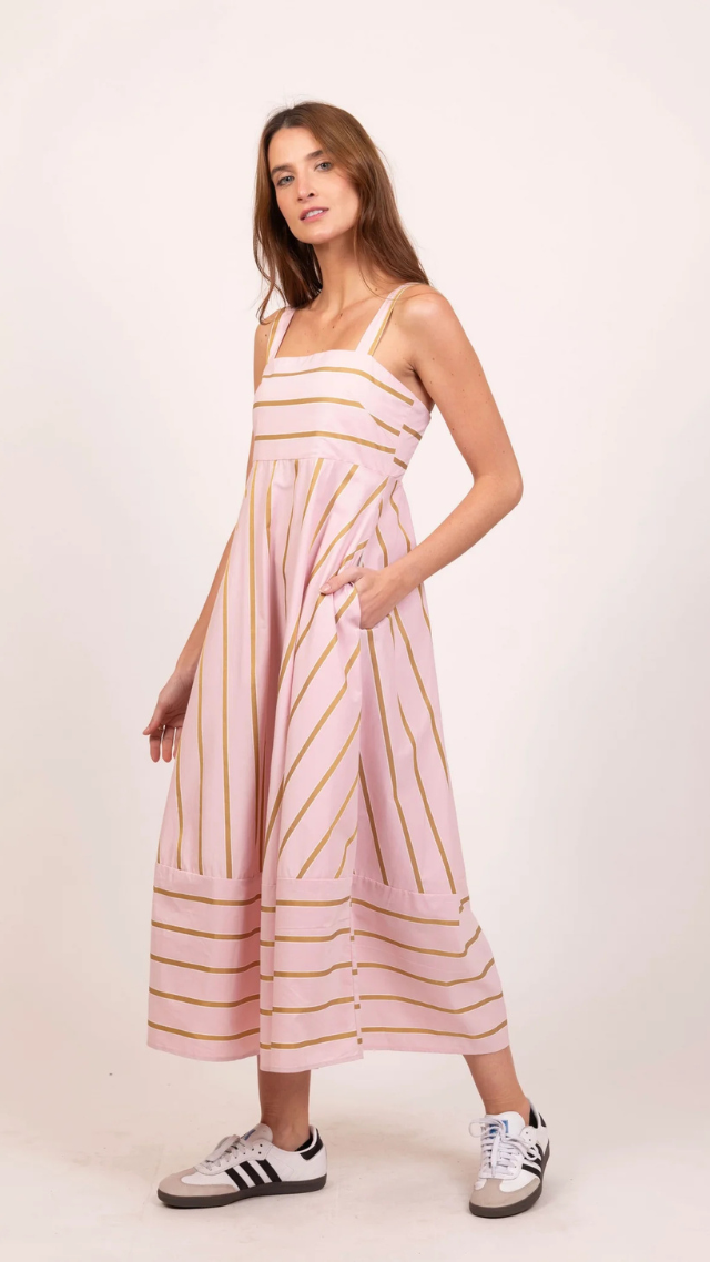 Model wearing the Amelia Midi Dress in blush pink with mustard stripes, featuring wide straps, a square neckline, and full A-line skirt with pockets.